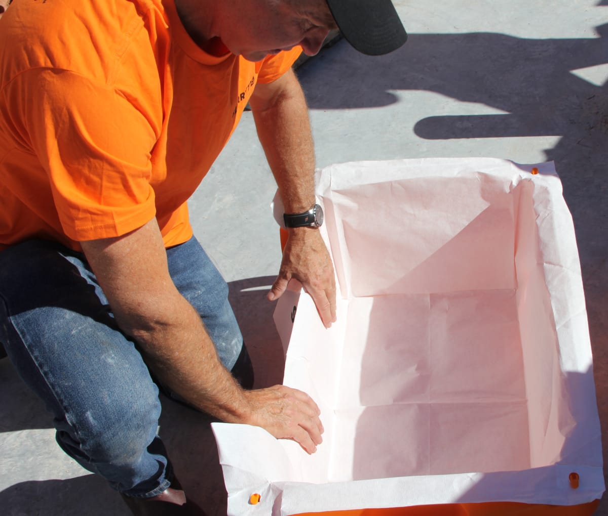 Man in orange shirt kneeling and putting a filter into a slurrytub. 